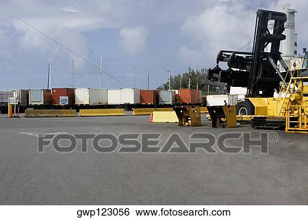 Forklift at a commercial dock with cargo containers in the background View Large Photo Image Stock Photograph - Forklift at a commercial dock with cargo containers in the background. Fotosearch