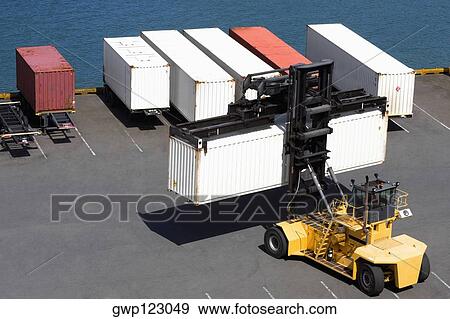 Stock Photo - High angle view of a forklift picking up a cargo container at a commercial dock. Fotosearch