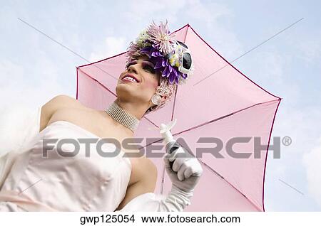 Picture - Close-up of a mid adult man holding an umbrella and smiling. Fotosearch