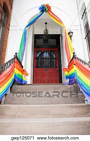 Stock Image - Gay pride flag decoration leading to a door. Fotosearch