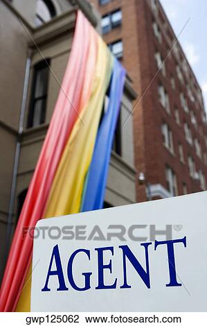 Signboard in front of a rainbow flag hanging from a building View Large Photo Image Stock Image - Signboard in front of a rainbow flag hanging from a building. Fotosearch