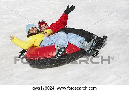 Picture - Boy and a girl sliding with an inner tube in snow. Fotosearch