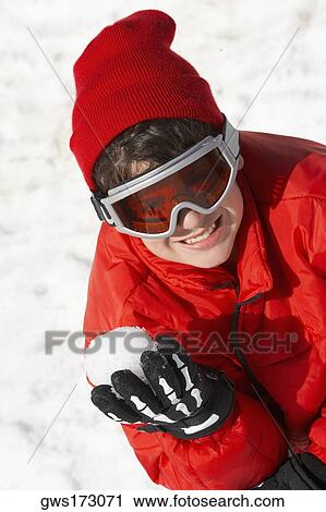Stock Image - High angle view of a boy holding a snowball and smiling. Fotosearch