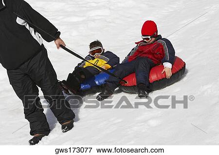 Low section view of a person pulling an inner tube with his children sitting on it View Large Photo Image Stock Photo - Low section view of a person pulling an inner tube with his children sitting on it. Fotosearch