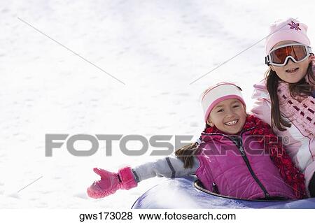 Mid adult woman with her daughter sliding down snowy slope on an inner tube View Large Photo Image Stock Photo - Mid adult woman with her daughter sliding down snowy slope on an inner tube. Fotosearch