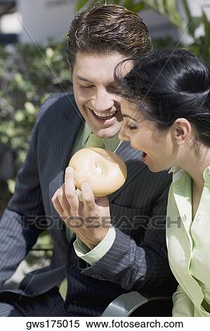 Businessman feeding a donut to a businesswoman smiling View Large Photo Image Stock Photography - Businessman feeding a donut to a businesswoman smiling. Fotosearch
