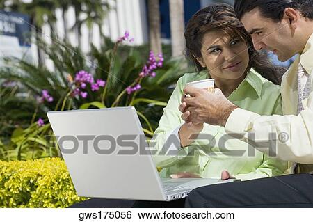 Businesswoman and a businessman sitting in front of a laptop and holding a cup of coffee View Large Photo Image Stock Photograph - Businesswoman and a businessman sitting in front of a laptop and holding a cup of coffee. Fotosearch