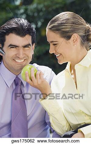 Businesswoman feeding a green apple to a businessman and smiling View Large Photo Image Stock Image - Businesswoman feeding a green apple to a businessman and smiling. Fotosearch