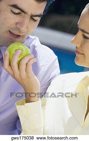 Close-up of a businesswoman feeding a green apple to a businessman View Large Photo Image Stock Photo - Close-up of a businesswoman feeding a green apple to a businessman. Fotosearch