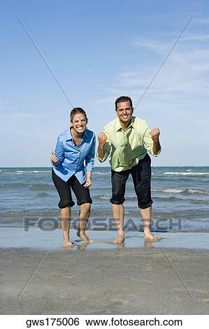 Mid adult couple clenching their fists on the beach View Large Photo Image Stock Photograph - Mid adult couple clenching their fists on the beach. Fotosearch