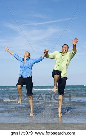 Mid adult couple jumping with holding each other hands on the beach View Large Photo Image Stock Photo - Mid adult couple jumping with holding each other hands on the beach. Fotosearch
