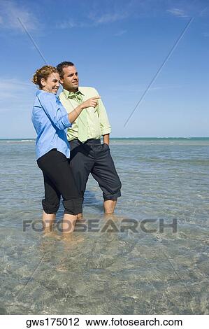 Mid adult couple standing in water View Large Photo Image Stock Image - Mid adult couple standing in water. Fotosearch