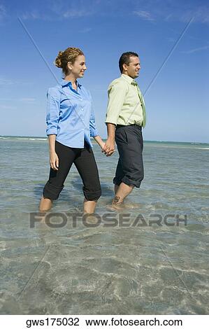 Mid adult couple wading on the beach with holding their hands View Large Photo Image Stock Image - Mid adult couple wading on the beach with holding their hands. Fotosearch