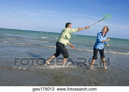 Mid adult man holding a fishing net over a mid adult woman on the beach View Large Photo Image Stock Image - Mid adult man holding a fishing net over a mid adult woman on the beach. Fotosearch