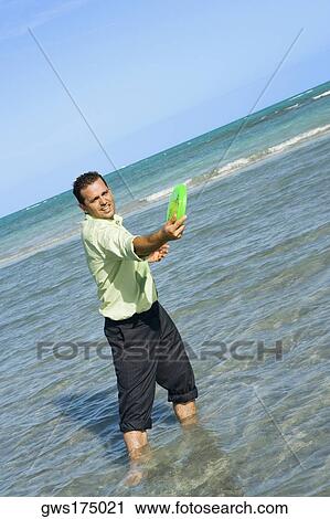 Mid adult man playing with a plastic disc on the beach View Large Photo Image Stock Image - Mid adult man playing with a plastic disc on the beach. Fotosearch