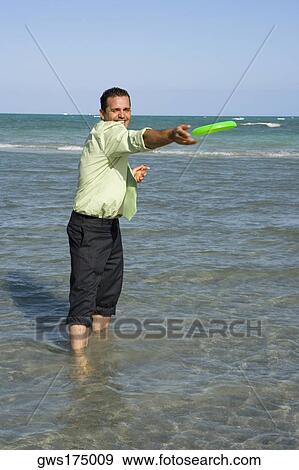 Mid adult man playing with a plastic disc on the beach View Large Photo Image Stock Photo - Mid adult man playing with a plastic disc on the beach. Fotosearch