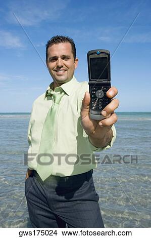 Picture - Mid adult man showing a flip phone and smiling. Fotosearch