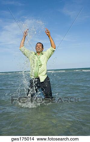 Mid adult man splashing water in the sea View Large Photo Image Picture - Mid adult man splashing water in the sea. Fotosearch