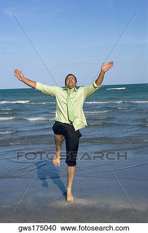 Mid adult man standing on his one leg on the beach View Large Photo Image Stock Image - Mid adult man standing on his one leg on the beach. Fotosearch
