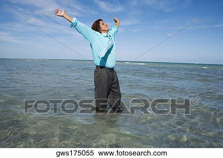 Mid adult man standing on the beach with his arms outstretched View Large Photo Image Stock Photography - Mid adult man standing on the beach with his arms outstretched. Fotosearch