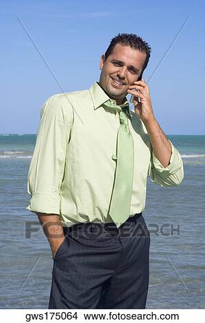 Picture - Mid adult man talking on a mobile phone and smiling. Fotosearch