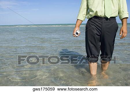Mid section view of a man holding a flip phone in water View Large Photo Image Stock Photo - Mid section view of a man holding a flip phone in water. Fotosearch