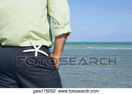 Mid section view of a man standing on the beach with his hands in his pockets View Large Photo Image Stock Image - Mid section view of a man standing on the beach with his hands in his pockets. Fotosearch