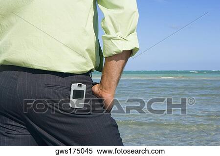 Mid section view of a man standing on the beach with his hands in his pockets View Large Photo Image Stock Photography - Mid section view of a man standing on the beach with his hands in his pockets. Fotosearch