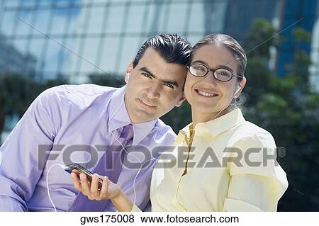 Portrait of a businessman and a businesswoman listening to an MP3 player View Large Photo Image Stock Photo - Portrait of a businessman and a businesswoman listening to an MP3 player. Fotosearch