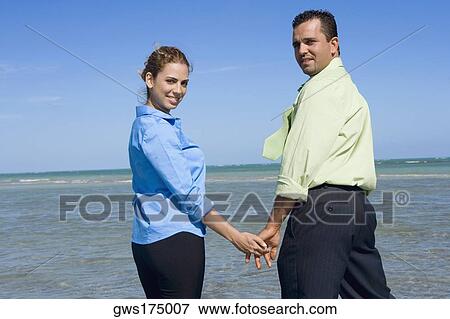 Portrait of a mid adult couple standing on the beach with holding their hands View Large Photo Image Stock Photo - Portrait of a mid adult couple standing on the beach with holding their hands. Fotosearch