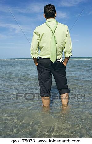 Rear view of a mid adult man standing on the beach with his hands in his pockets View Large Photo Image Stock Image - Rear view of a mid adult man standing on the beach with his hands in his pockets. Fotosearch