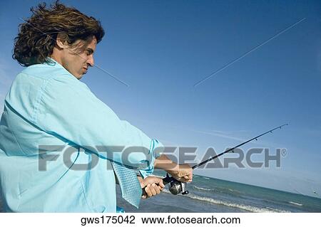 Side profile of a mid adult man holding a fishing rod on the beach View Large Photo Image Stock Image - Side profile of a mid adult man holding a fishing rod on the beach. Fotosearch