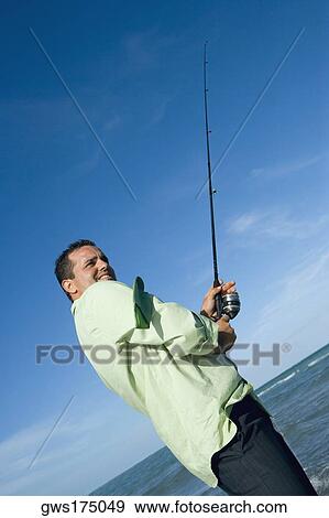 Side profile of a mid adult man holding a fishing rod on the beach View Large Photo Image Stock Photo - Side profile of a mid adult man holding a fishing rod on the beach. Fotosearch