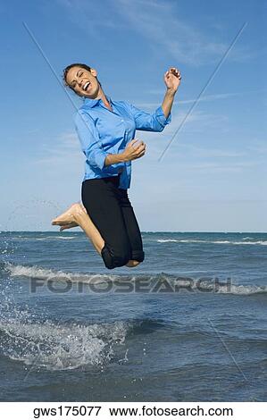 Stock Photo - Side profile of a mid adult woman jumping on the beach. Fotosearch