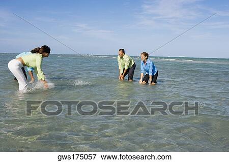 Side profile of two mid adult couples splashing water on each other on the beach View Large Photo Image Stock Photo - Side profile of two mid adult couples splashing water on each other on the beach. Fotosearch