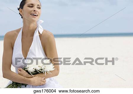 Close-up of a young woman holding a bunch of flowers on the beach View Large Photo Image Picture - Close-up of a young woman holding a bunch of flowers on the beach. Fotosearch