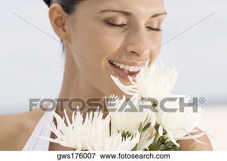 Close-up of a young woman smelling flowers View Large Photo Image Stock Photo - Close-up of a young woman smelling flowers. Fotosearch