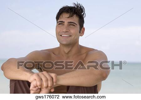Mid adult man sitting on the beach and smiling View Large Photo Image Stock Image - Mid adult man sitting on the beach and smiling. Fotosearch