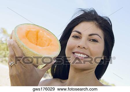 Stock Photo - Portrait of a mid adult woman holding a half melon and smiling. Fotosearch