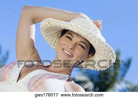 Portrait of a mid adult woman wearing a straw hat and smiling View Large Photo Image Stock Photo - Portrait of a mid adult woman wearing a straw hat and smiling. Fotosearch