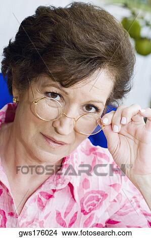 Portrait of a senior woman peeking over her eyeglasses View Large Photo Image Picture - Portrait of a senior woman peeking over her eyeglasses. Fotosearch