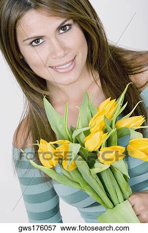 Portrait of a young woman holding flowers and smiling View Large Photo Image Stock Photo - Portrait of a young woman holding flowers and smiling. Fotosearch