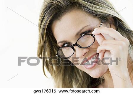 Portrait of a young woman peeking over her eyeglasses View Large Photo Image Stock Photography - Portrait of a young woman peeking over her eyeglasses. Fotosearch