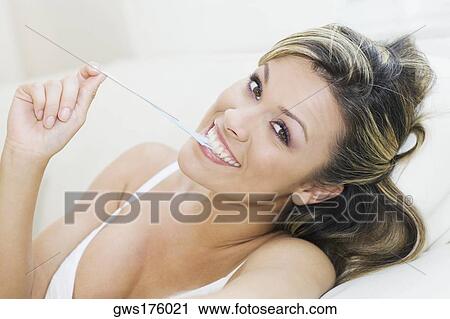 Stock Image - Portrait of a young woman pulling a bubble gum from her mouth. Fotosearch