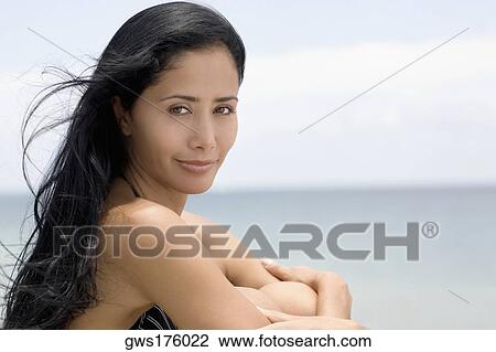 Portrait of a young woman sitting on the beach with hugging her knees View Large Photo Image Stock Image - Portrait of a young woman sitting on the beach with hugging her knees. Fotosearch