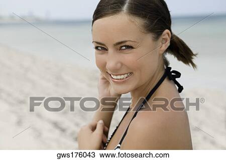Stock Image - Portrait of a young woman smiling on the beach. Fotosearch