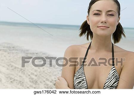 Stock Image - Portrait of a young woman smirking on the beach. Fotosearch