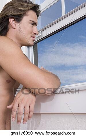 Side profile of a young man looking through a window View Large Photo Image Stock Image - Side profile of a young man looking through a window. Fotosearch
