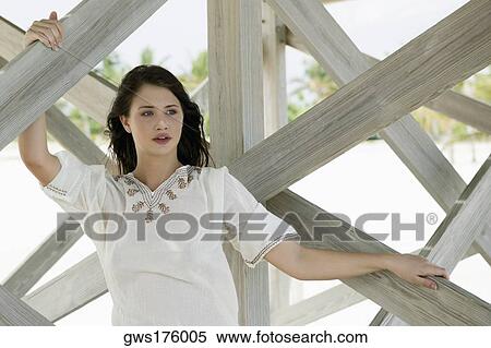 Young woman leaning against a wooden structure on the beach View Large Photo Image Stock Photography - Young woman leaning against a wooden structure on the beach. Fotosearch