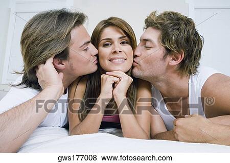 Close-up of a mid adult man and a young man kissing a young woman View Large Photo Image Stock Photo - Close-up of a mid adult man and a young man kissing a young woman. Fotosearch